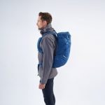 Osoba s batohem Montane Traiblazer 30 na zádech z boku v modré barvě.