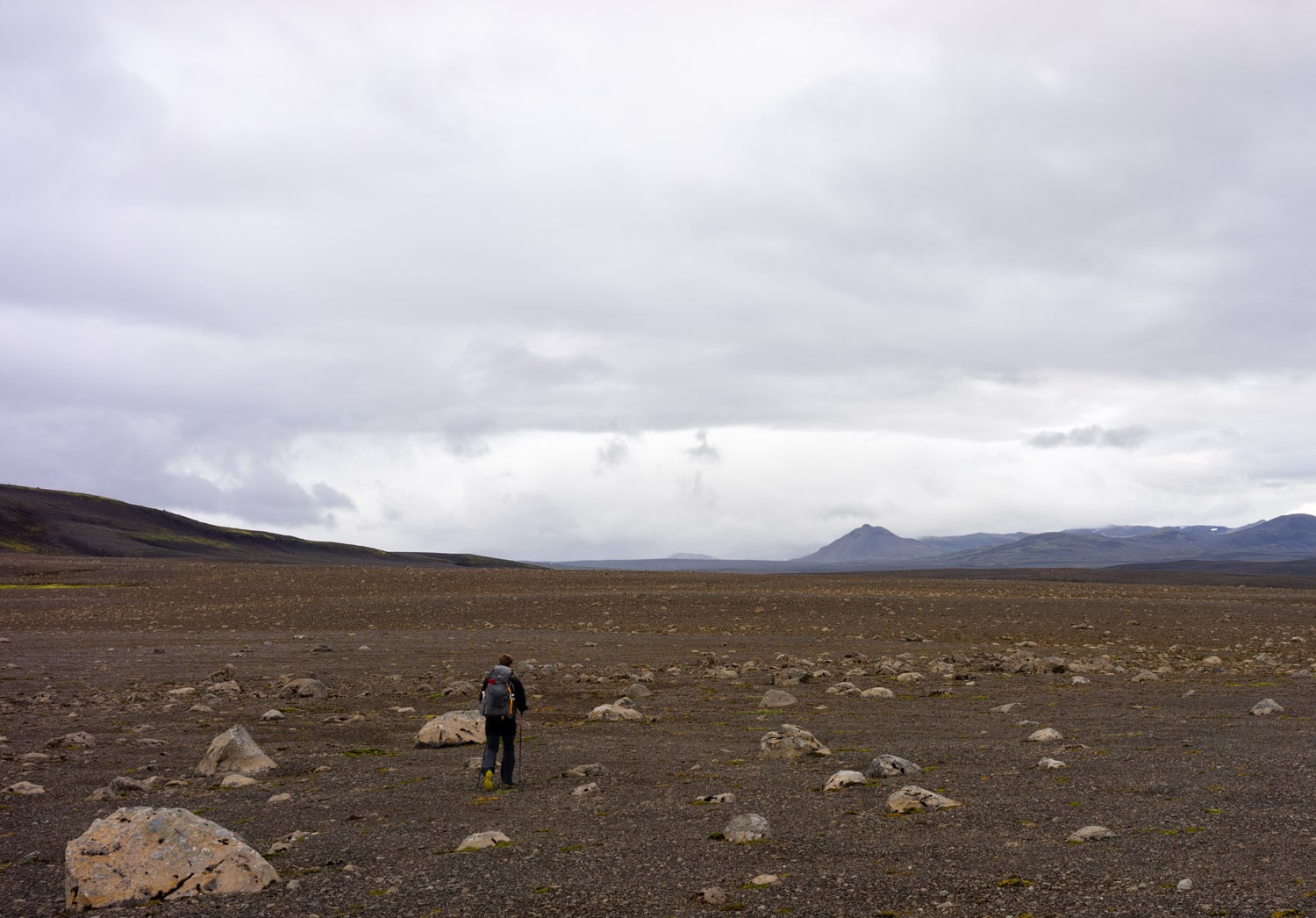 Osoba s ultralehkým batohem, jdoucí pustou krajinou na Islandu.