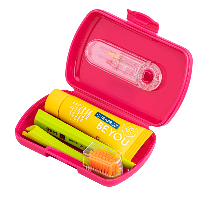Open pink travel dental kit containing a BEYOU toothpaste tube, two lime-green toothbrushes, and a small orange-bristled brush.