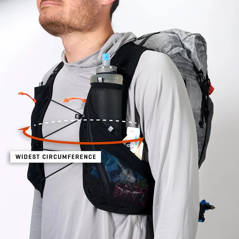 Man wearing a hydration vest and backpack, with two water bottles in side pockets and elastic cords for gear; label and arrows highlight widest circumference for fit.