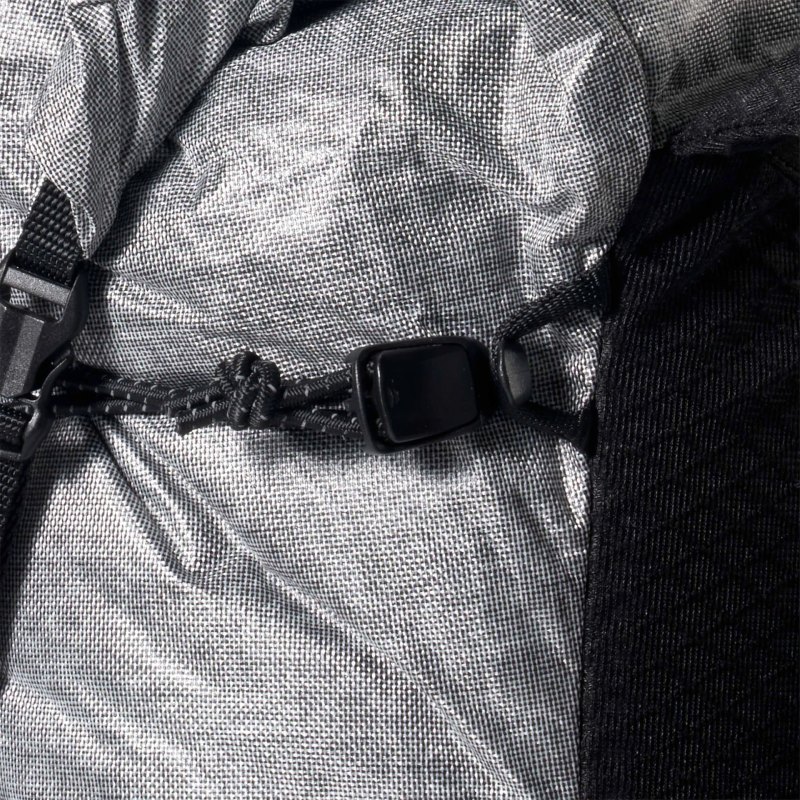 Close-up of a backpack strap with a black plastic buckle on gray fabric.