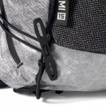 Close-up of a gray and black backpack showing zipper pulls and textured fabric surface.