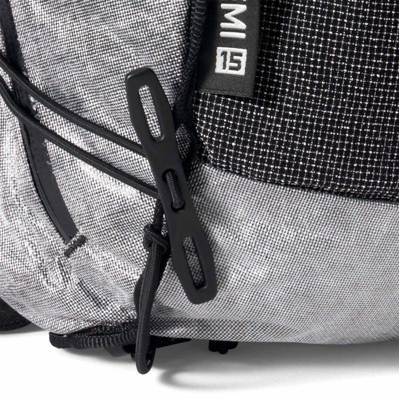 Close-up of a gray and black backpack showing zipper pulls and textured fabric surface.