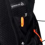 Close-up of a black Hyperlite Mountain Gear backpack showing an orange zipper pull and cord locks in the pocket.