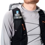 Hiker wearing a black hydration backpack; a water bottle sits in the right side pocket with orange zipper pulls in view.