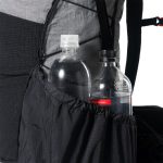 Backpack with two water bottles in the side pocket, one clear bottle with a white cap and the other with a black cap.