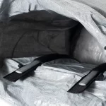 Close-up of the inside of a gray backpack revealing two black straps with metal sliders across the fabric pocket.