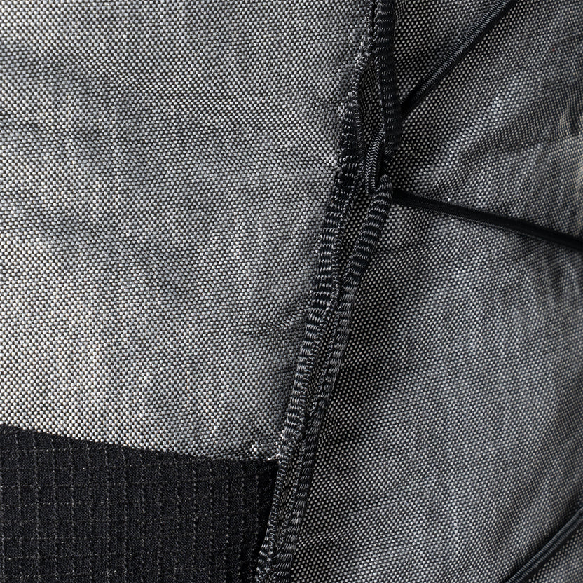 Close-up of gray, woven backpack fabric with a black zipper sewn along a seam.
