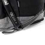 Close-up of a black ice axe strapped to a gray and black backpack, ready for mountaineering gear.