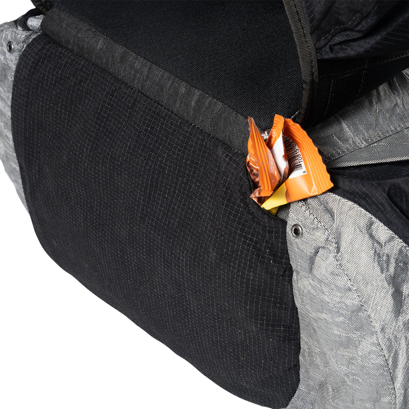 Backpack with an orange candy wrapper peeking out of a front pocket.