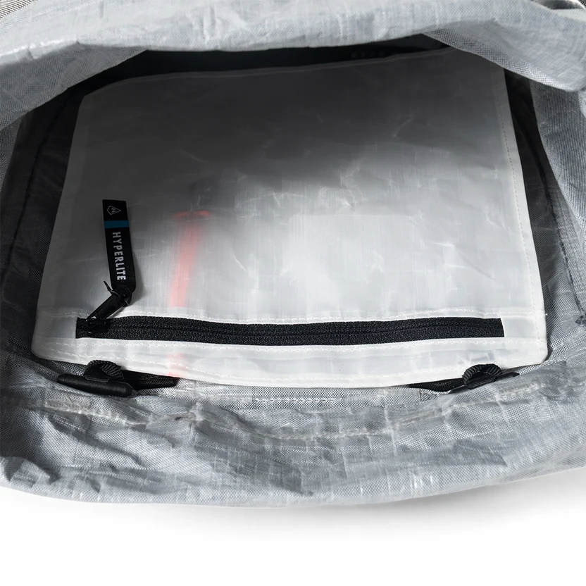 Inside view of a gray backpack with a white zippered pouch and black zipper pull inside the main compartment.