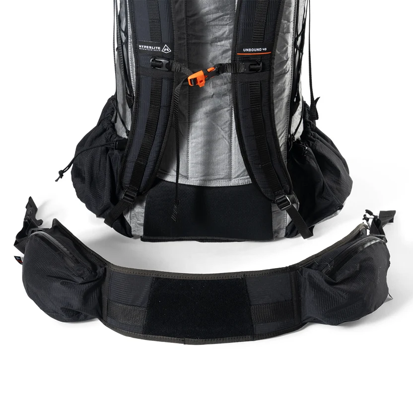 Backpack with a detachable padded hip belt laid out in front, showing waist straps and attachment points for hiking gear.