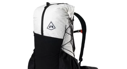 Hiking backpack with a white top section and black bottom, featuring side pockets and bungee cords for gear.