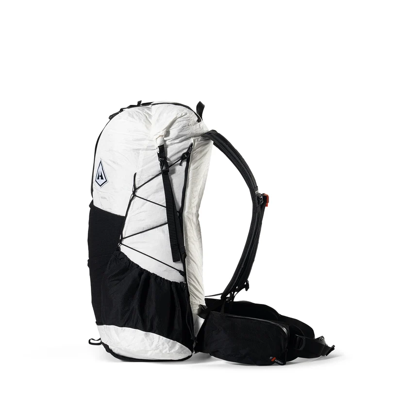 White and black hiking backpack with side pockets and crisscross bungee cords on the front panel, photographed from the side.