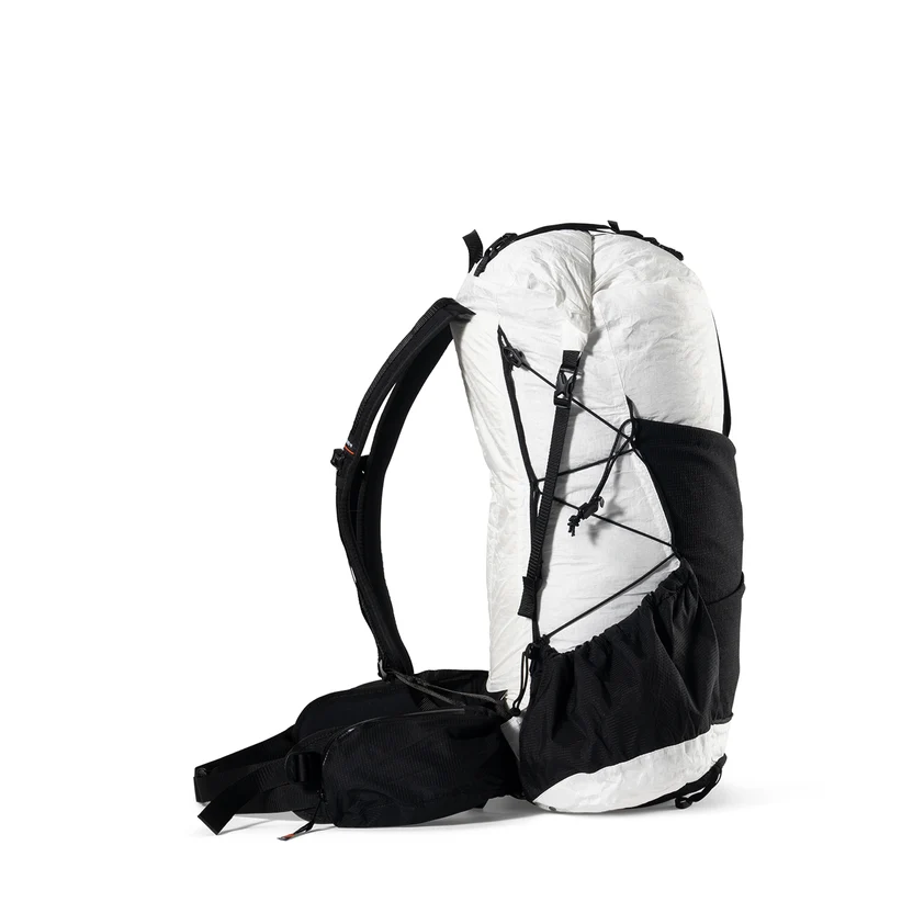 White and black hiking backpack standing upright against a white background, showing external bungee cords and side pocket access.