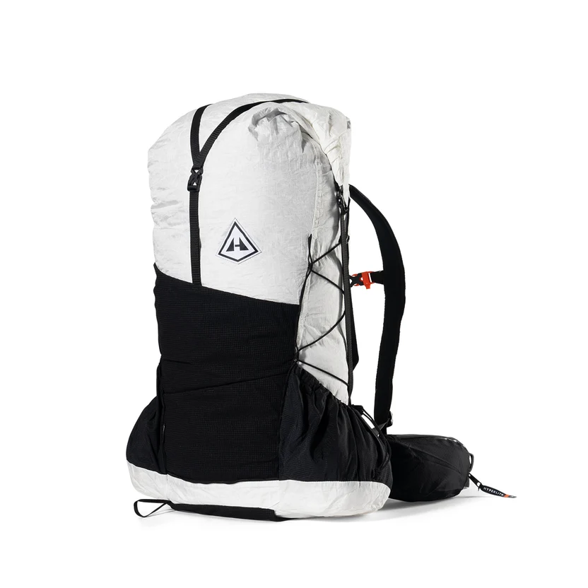 White and black alpine backpack with a large main compartment, front bungee cords, and a padded hip belt; features a side pocket and compact pack design.