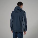 Montane Mens Norste Lite Jacket Eclipse Blue 03 Rear view of a person wearing a navy blue windbreaker against a gray studio backdrop, hood down.
