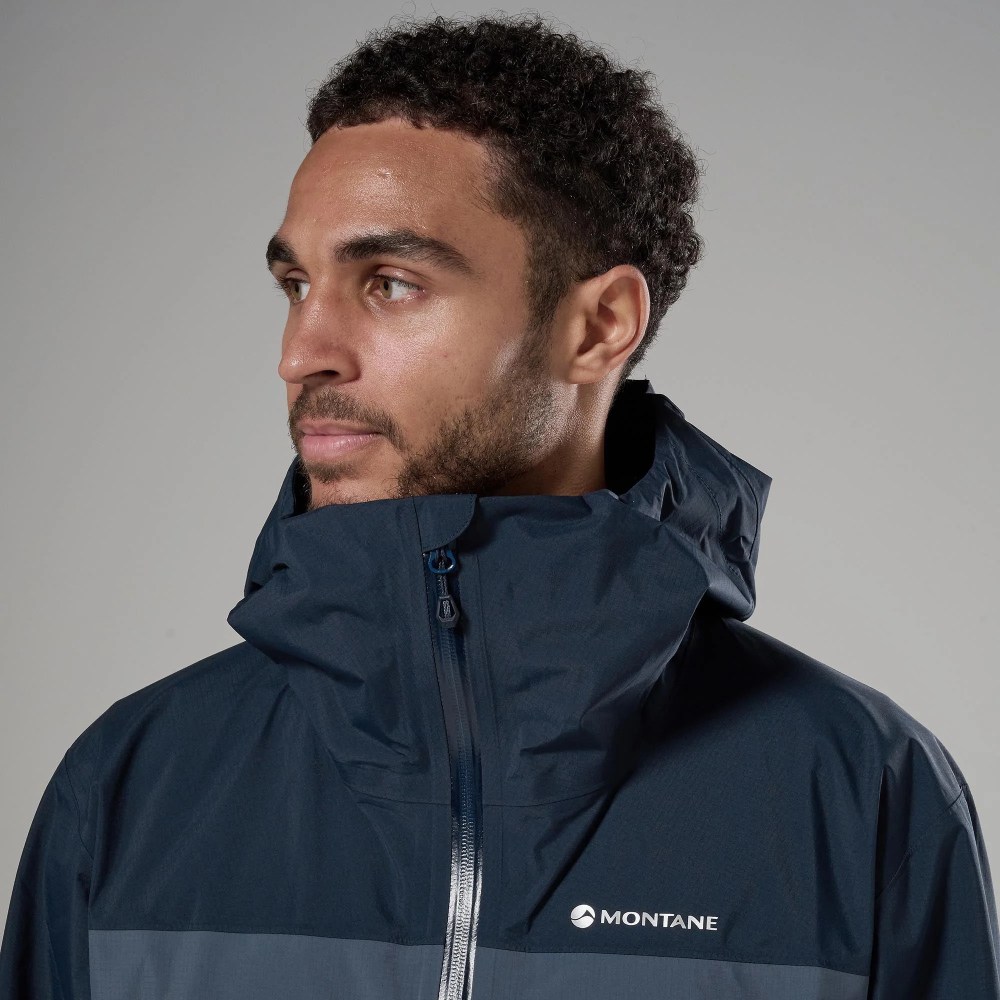 Man wearing a navy Montane waterproof jacket with high collar, facing left, neutral expression.