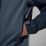 Montane Mens Norste Lite Jacket Eclipse Blue 06 Close-up of a navy outdoor jacket with a zippered side pocket and a hand resting in the pocket.