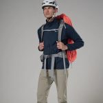 Montane Mens Zepher Jacket Eclipse Blue 04 Climber wearing a helmet and harness with a coiled red rope over the shoulder, standing ready for ascent.