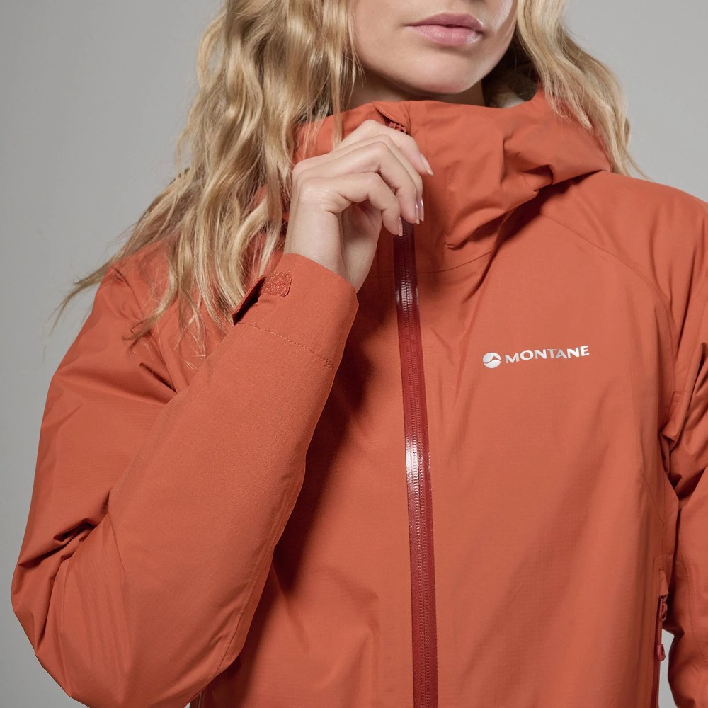 Close-up of an orange Montane windbreaker with a high collar and central zipper being adjusted by a hand.