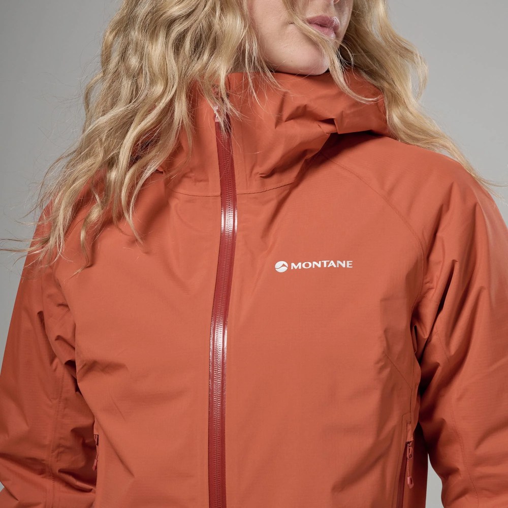 Montane Womens Norste Lite Jacket Lava 05 Close-up of an orange Montane waterproof jacket with a front zipper and the Montane logo on the chest.
