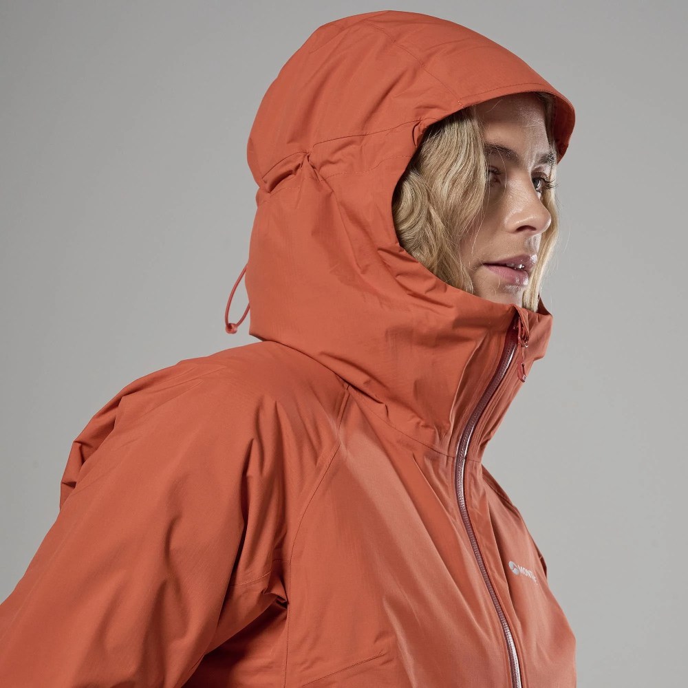 Side profile of a person wearing an orange hooded waterproof jacket, zipper up. around-right orientation and neutral background.