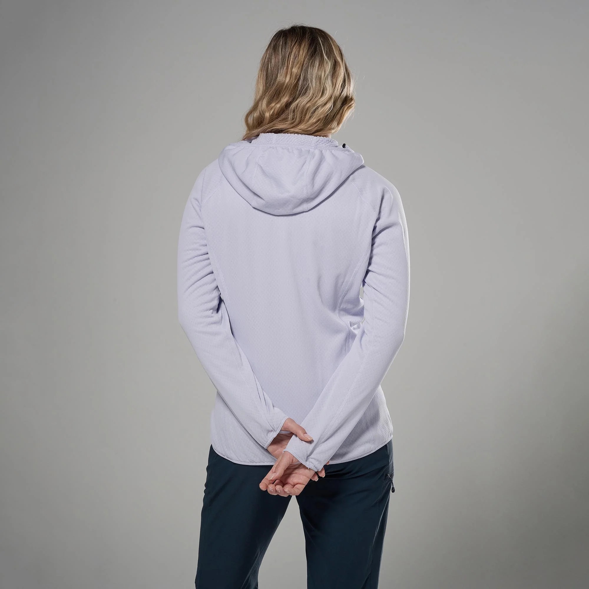 Montane Womens Zepher Hoodie Platinum 03 Person seen from behind wearing a light lavender hoodie, arms loosely crossed in front against a gray studio backdrop