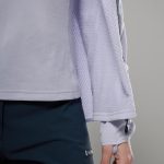 Montane Womens Zepher Hoodie Platinum 07 Close-up of a lavender fleece jacket sleeve and hem paired with dark navy pants, showing textured fabric and a zippered cuff detail.